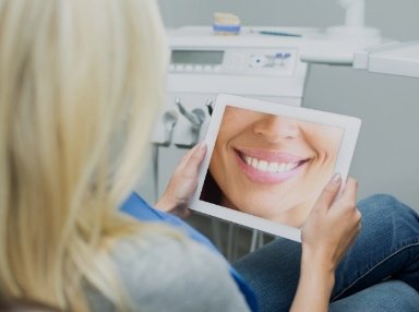 Woman looking at digital smile design on tablet computer